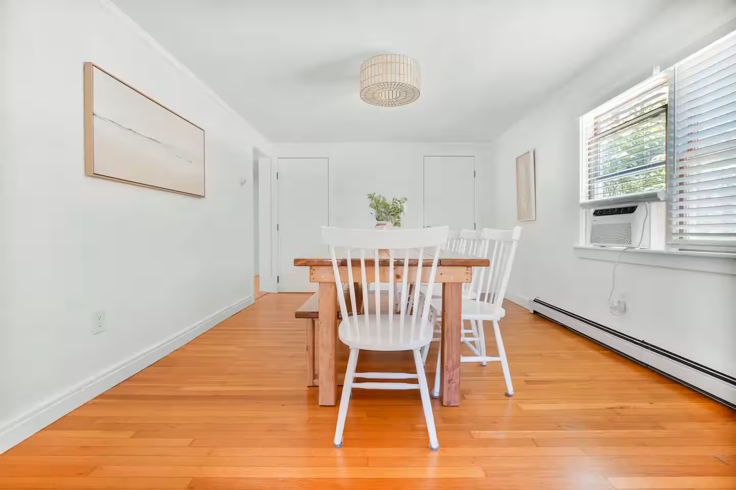 Minimalist dining room with white chairs and wooden floor.